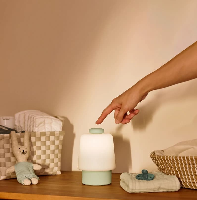 Hand touching the top button on a mint colorway Hatch baby on a changing station